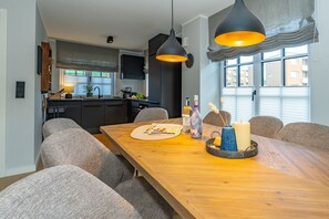 Un comedor moderno con una mesa de madera, sillas tapizadas en gris y luces colgantes.