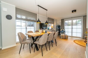 A modern dining area with a wooden table, grey upholstered chairs, and pendant lighting.