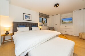 Une chambre moderne avec un grand lit, des tables de chevet, une armoire et un téléviseur.