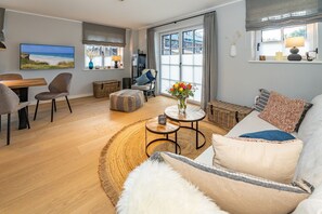 A modern living room with a wooden floor, a sofa, a coffee table, and a TV.