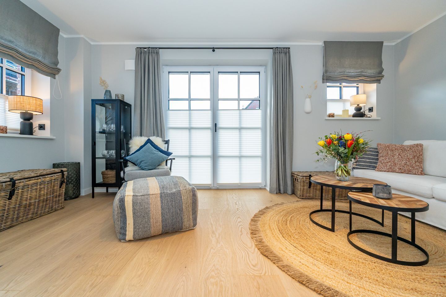 A modern living room with a large window, a sofa, a coffee table, and a side table.
