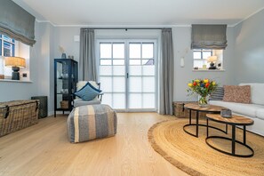 Una sala de estar moderna con un ventanal grande, un sofá, una mesita de centro y una mesita auxiliar.