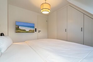 Un dormitorio con una cama, un cuadro de playa y un armario.