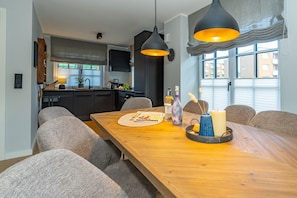 Ein moderner Essbereich mit einem Holztisch, grau gepolsterten Stühlen und Pendelleuchten.