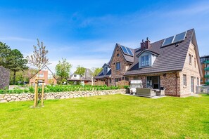 Une grande maison avec une façade en pierre, une pelouse bien entretenue et un mur en pierre.