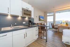 Une cuisine moderne dotée d’un four encastré, d’un évier et d’un coin repas avec une table et des chaises.