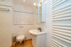 A bathroom with a toilet, sink, and mirror. - Sylter Meerzeit - 1-room vacation apartment close to the city and beach in Westerland with (Sylt)