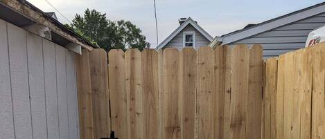 A wooden fence with a black latch in a backyard.