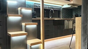 A modern kitchen with a wooden staircase leading to an upper level.