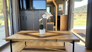 A modern kitchen with dark cabinets, a wooden dining table, and a potted orchid.