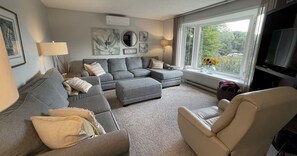 Relax in this stylish living room with a large sofa, armchair, and flat-screen TV.