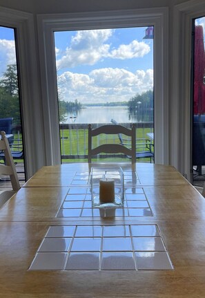 Enjoy meals with a serene lake view from this dining area featuring a large table and comfortable seating for two.