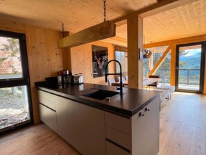 A wooden interior with a kitchen island, a sink, and a dining area with a view.