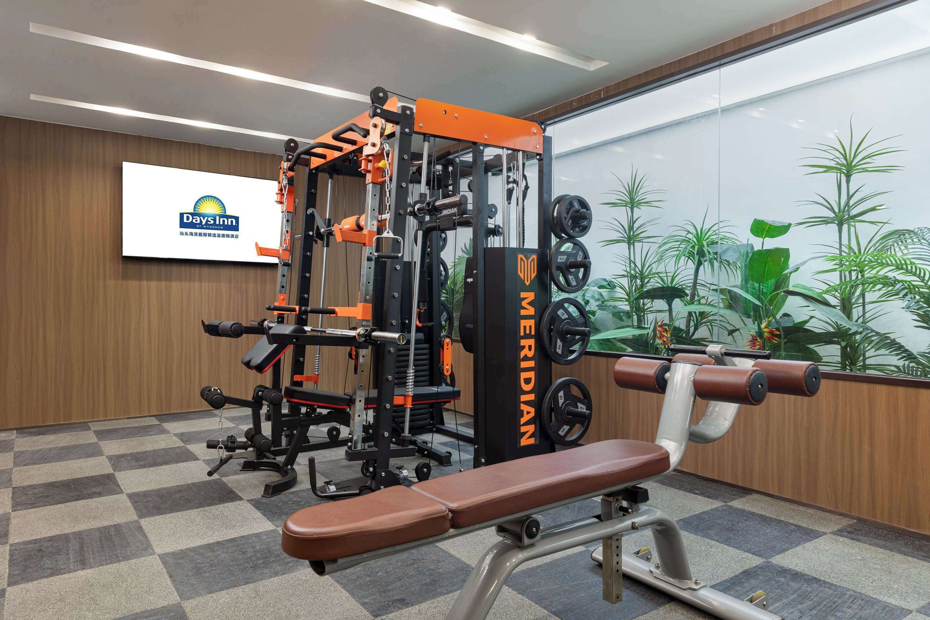 A gym with a bench, weight machines, and a wall-mounted sign for Days Inn.