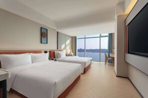 A hotel room with two beds, a large TV, and a view of the water. - Days Inn by Wyndham Shantou Jinping (Shantou)