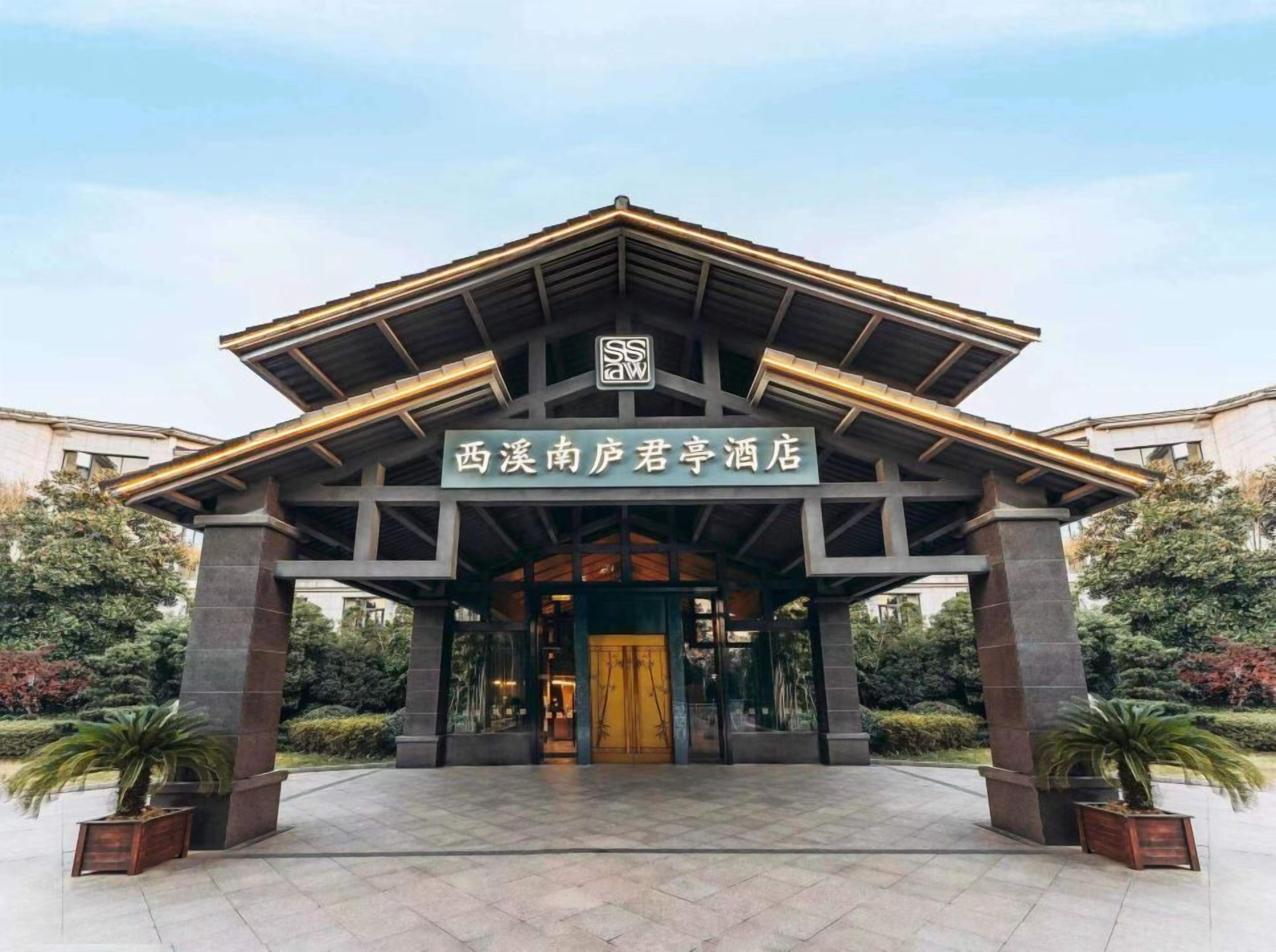 A hotel entrance with a sign in Chinese characters, a modern architectural design, and a paved entrance area.