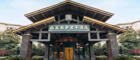 A hotel entrance with a sign in Chinese characters, a modern architectural design, and a paved entrance area.