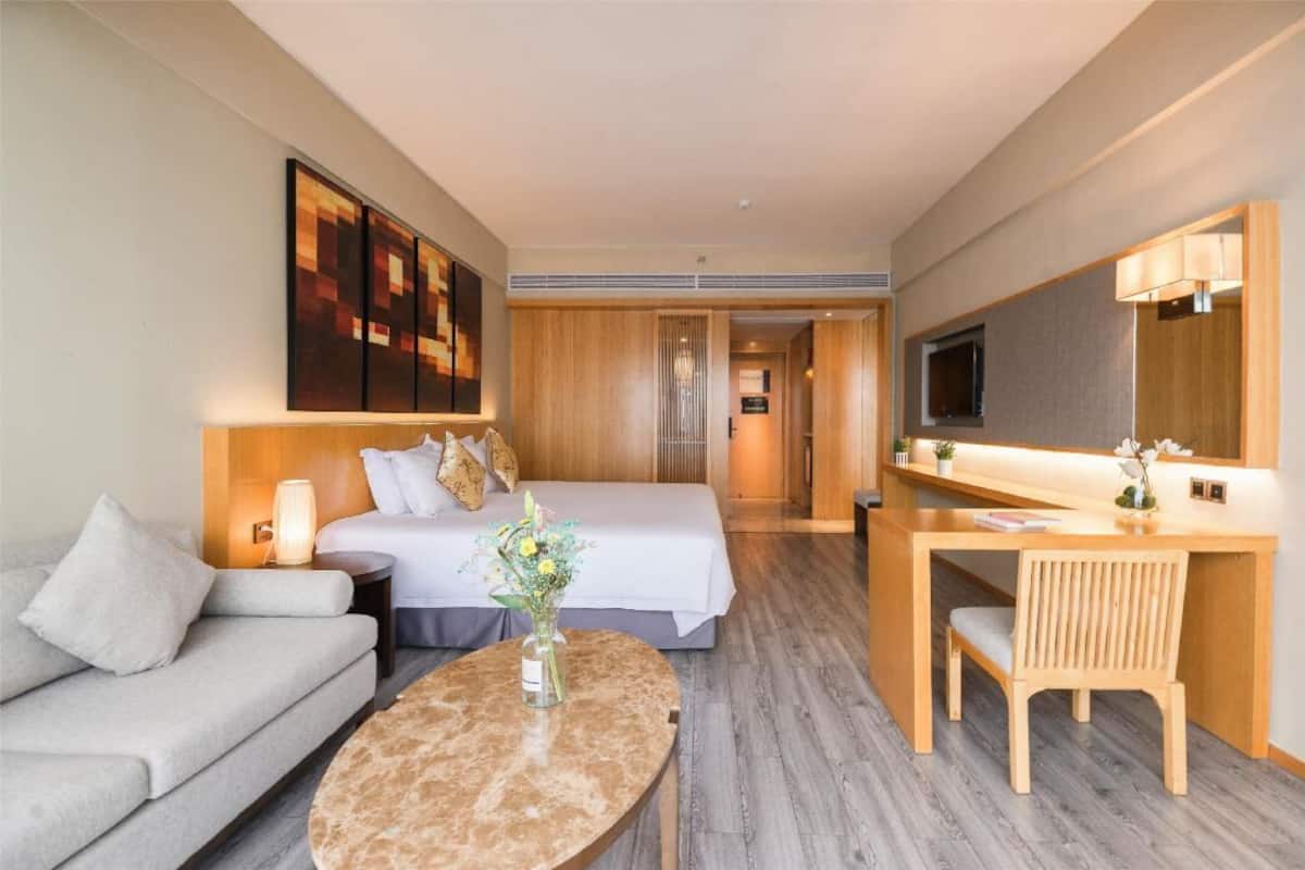 A hotel room with a bed, a sofa, a desk, and a TV.