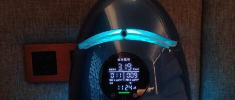 A smart speaker with a digital display, placed on a table against a textured wall.