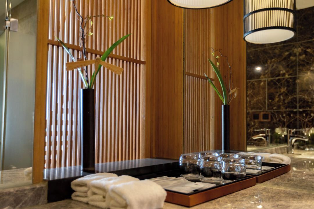 A spa area with a wooden partition, a massage table, towels, and glass containers on a tray.
