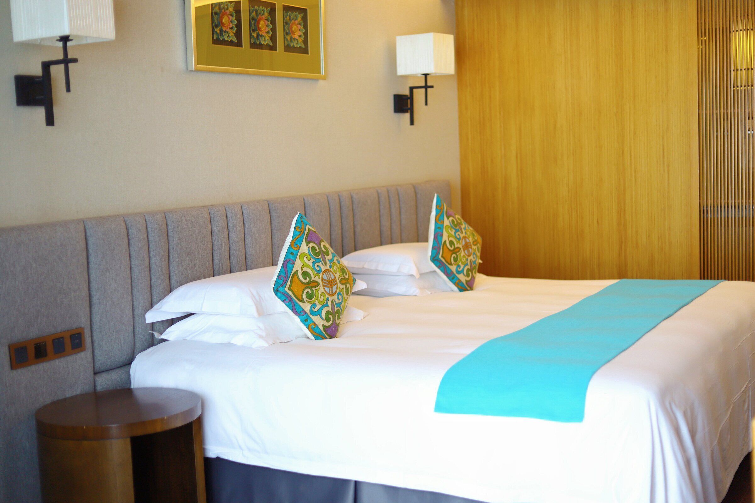 Una habitación de hotel con una cama grande, dos mesitas de noche y un cabecero de madera.