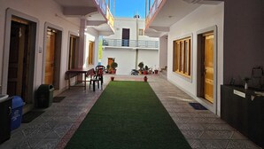 A courtyard with a central green carpet, potted plants, and a reception desk. - LUNGDHO RESIDENCY (Leh)