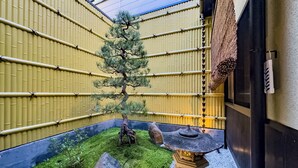 A traditional Japanese garden with a pine tree, rocks, and a stone lantern.