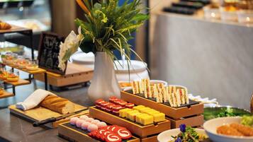 A buffet with various food items, including sandwiches, pastries, and desserts.