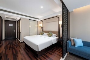 A modern hotel room with a large bed, a blue sofa, and a decorative partition. - SSAW Boutique Hotel Hangzhou East Railway Station - Close to West Lake (Hangzhou)