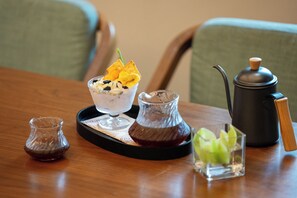 A tray with a dessert, a glass of beverage, a small pitcher, and a coffee pot on a wooden table. - SSAW Boutique Hotel Hangzhou East Railway Station - Close to West Lake (Hangzhou)