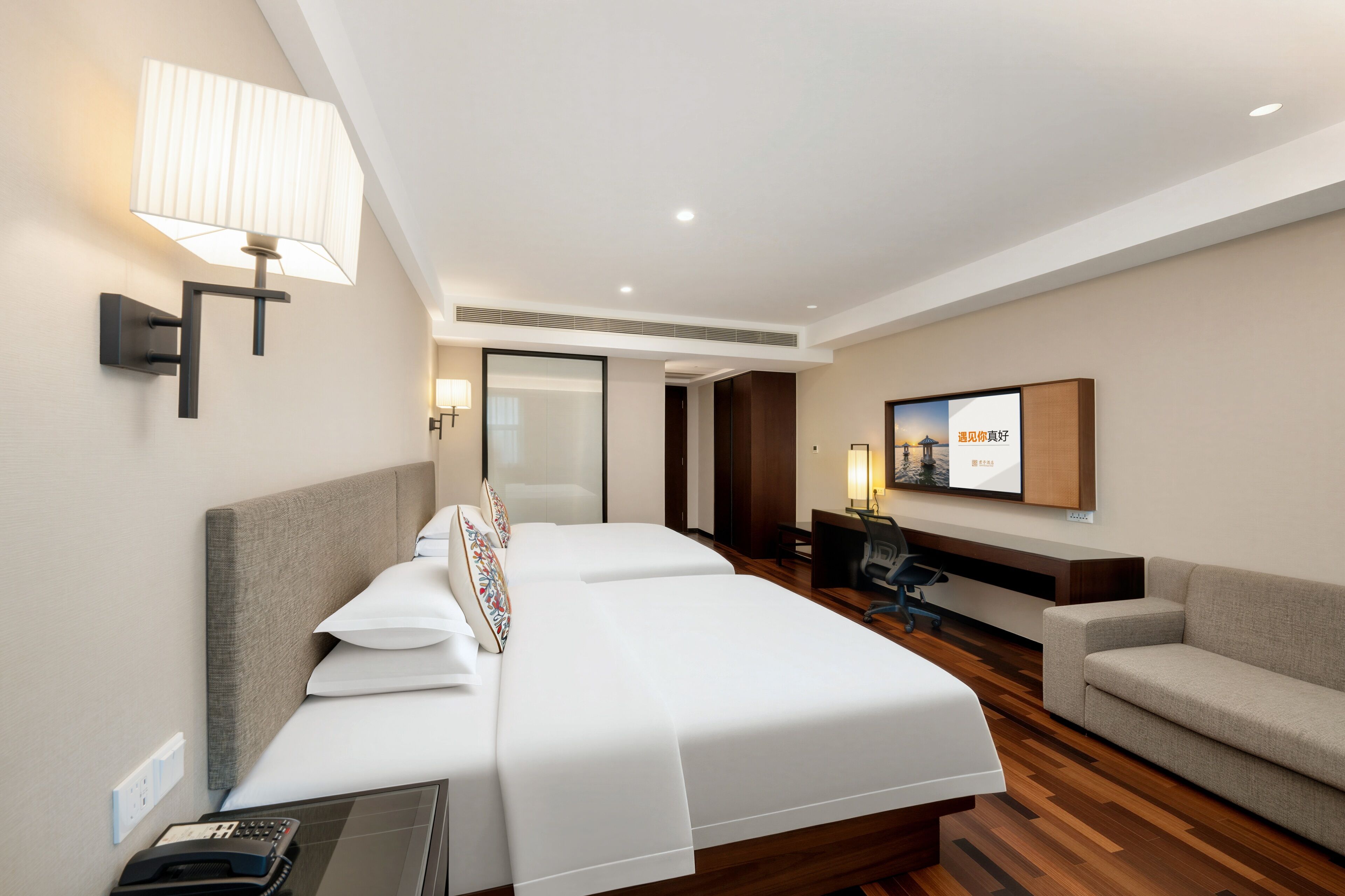 A hotel room with a bed, a desk, a chair, and a TV.