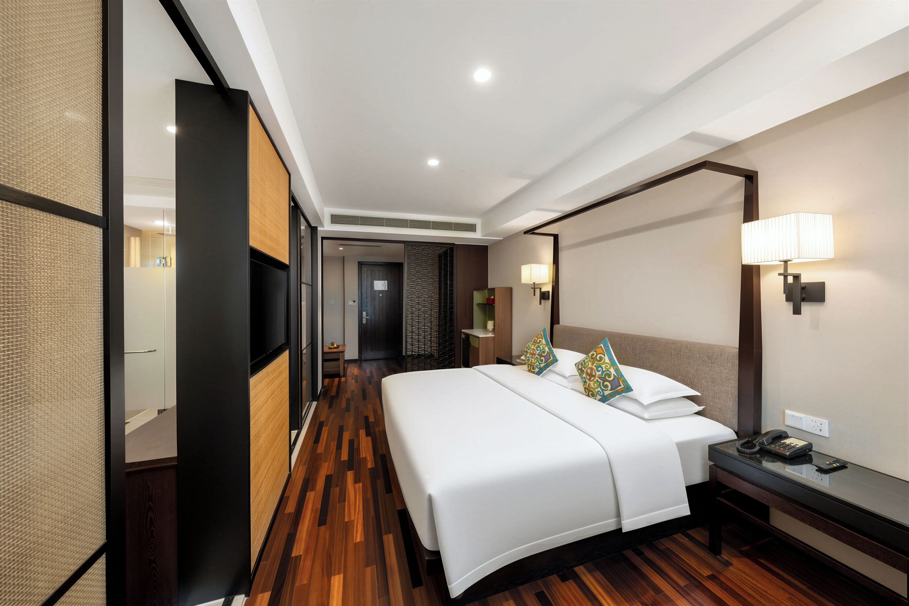 Una habitación de hotel con una cama grande, mesitas de noche, un escritorio y una lámpara.