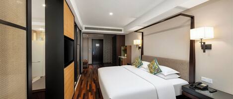 Una habitación de hotel con una cama grande, mesitas de noche, un escritorio y una lámpara.