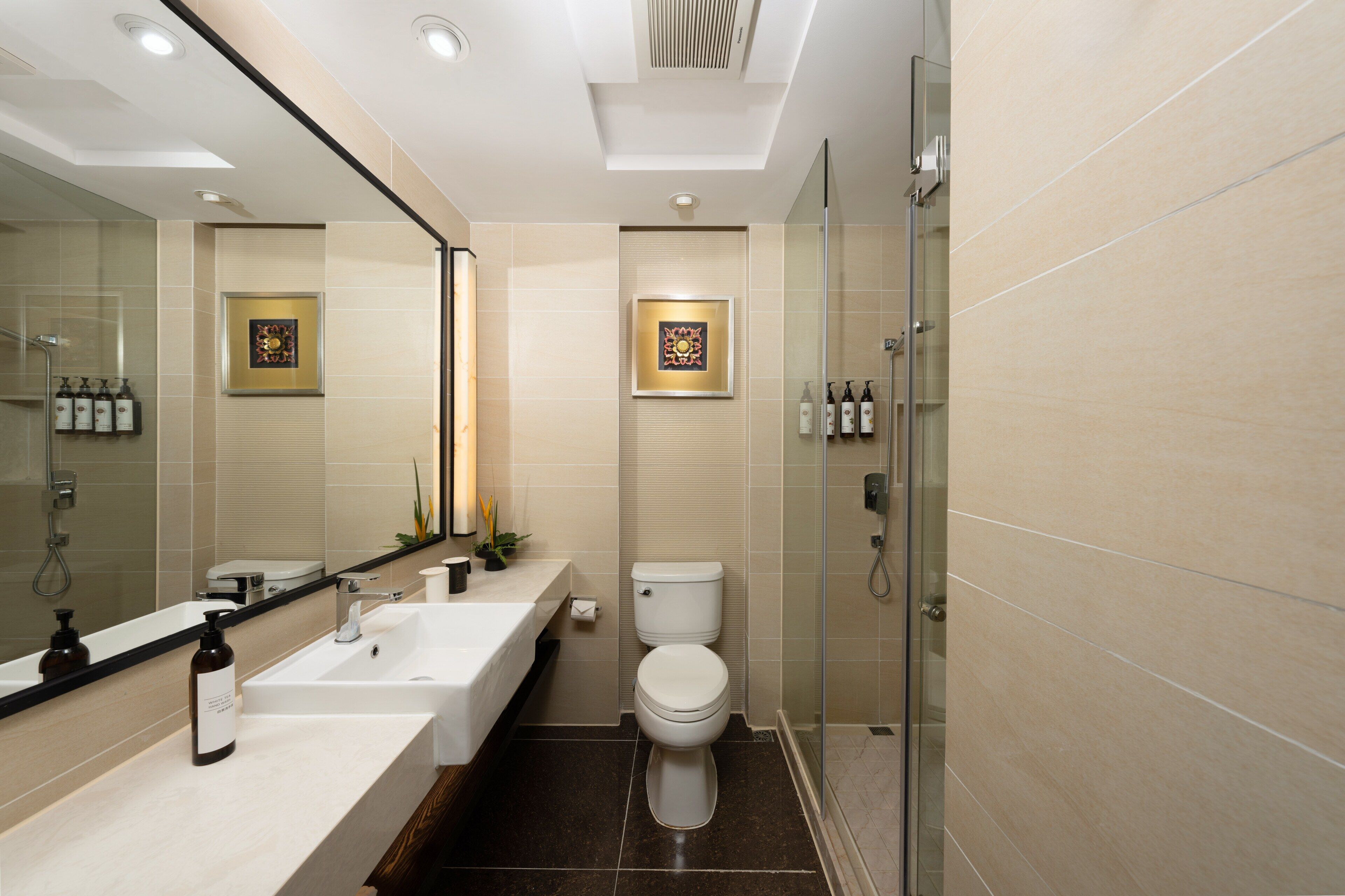 A modern bathroom with a glass shower enclosure, a white sink, and a toilet.