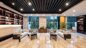A modern lobby with a sofa set, bookshelves, a coffee station, and large windows. - SSAW Boutique Hotel Hangzhou East Railway Station - Close to West Lake (Hangzhou)