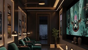 Ein modernes Interieur mit dunklen Wänden, grünen Sitzgelegenheiten und einem großen Bildschirm, der Kunstwerke zeigt.