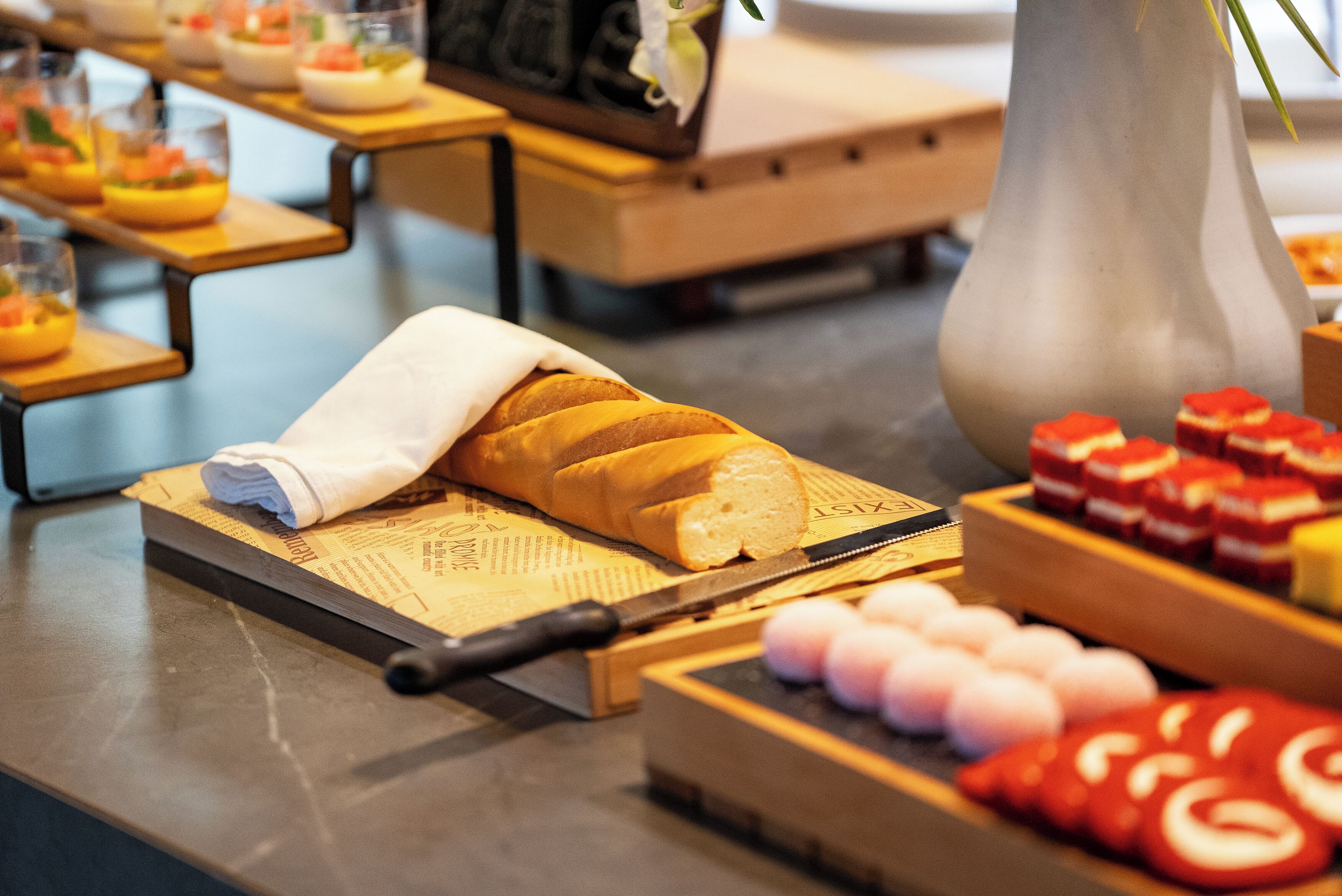 A table with a loaf of bread, a knife, and various food items.