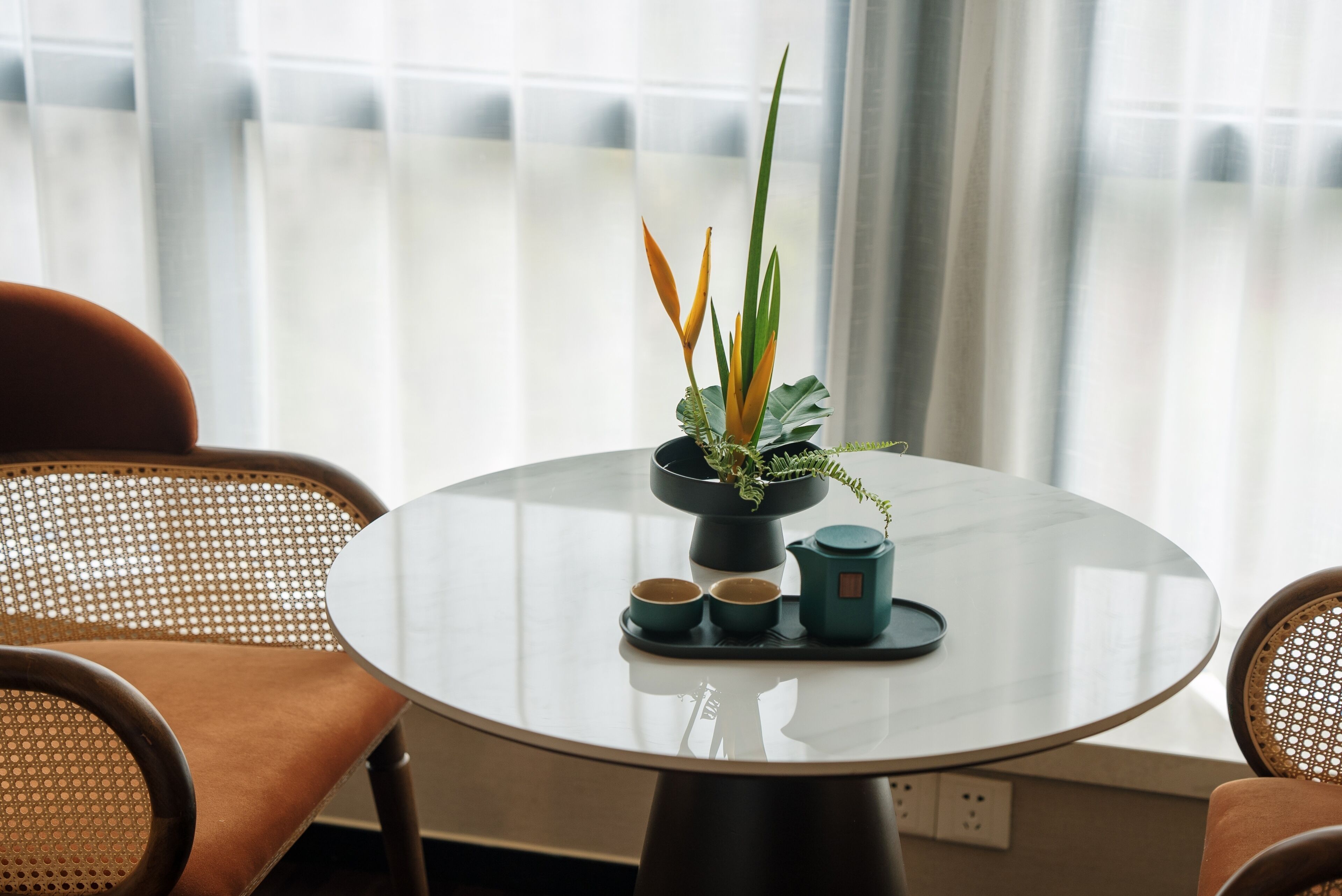 A round table with a potted plant, two cups, and a teapot.