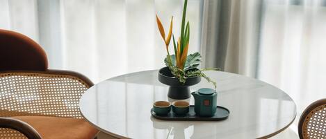 A round table with a potted plant, two cups, and a teapot.