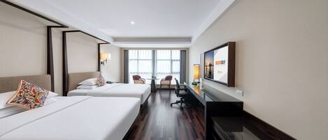 Een hotelkamer met twee bedden, een bureau, een stoel, een televisie en een raam met uitzicht.
