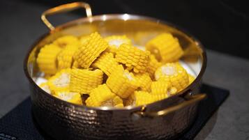 A pot with a handle containing corn cobs.