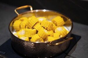 A pot with a handle containing corn cobs.