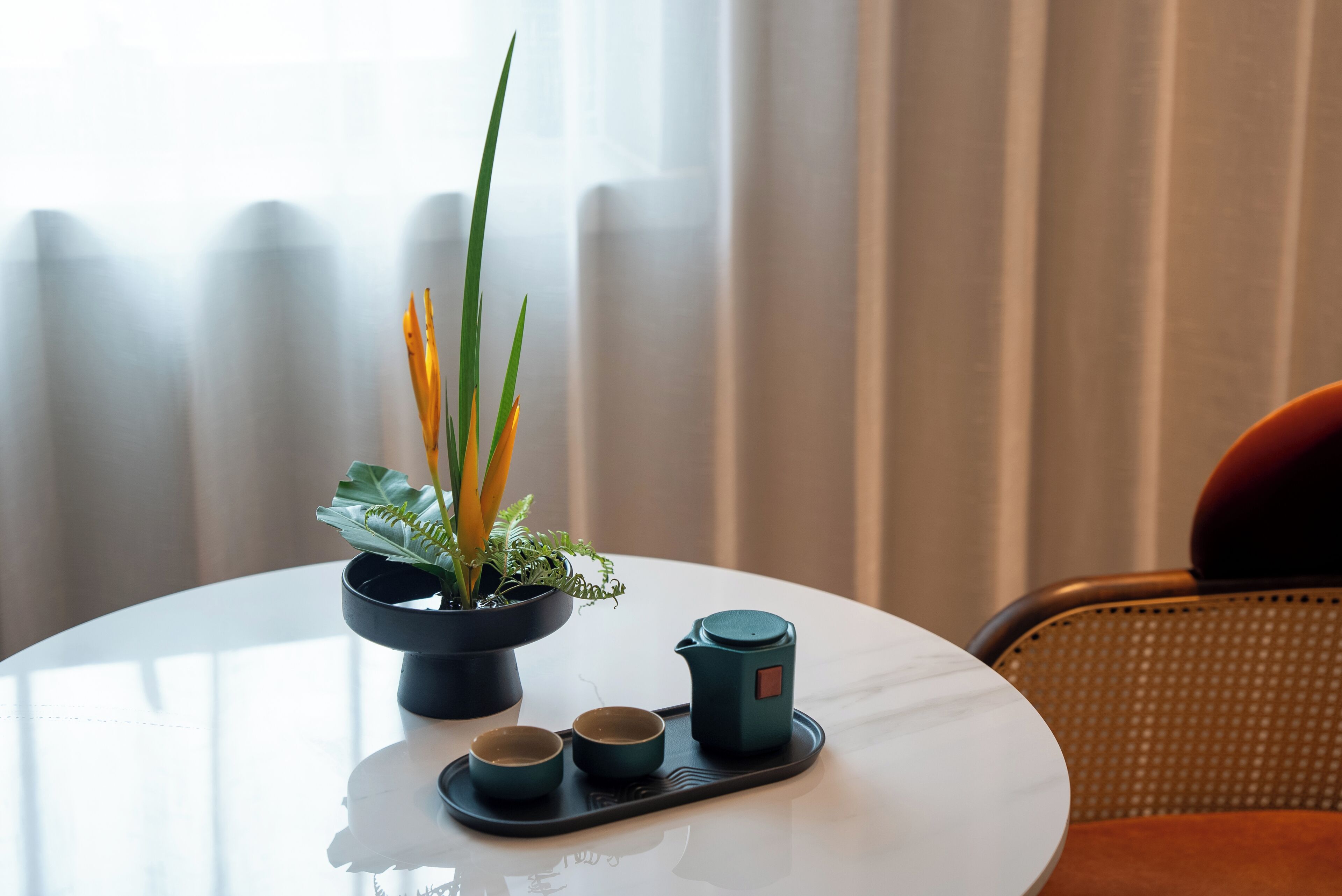 Ein runder Tisch mit einem Blumentopf, zwei Tassen und einem Teekessel.