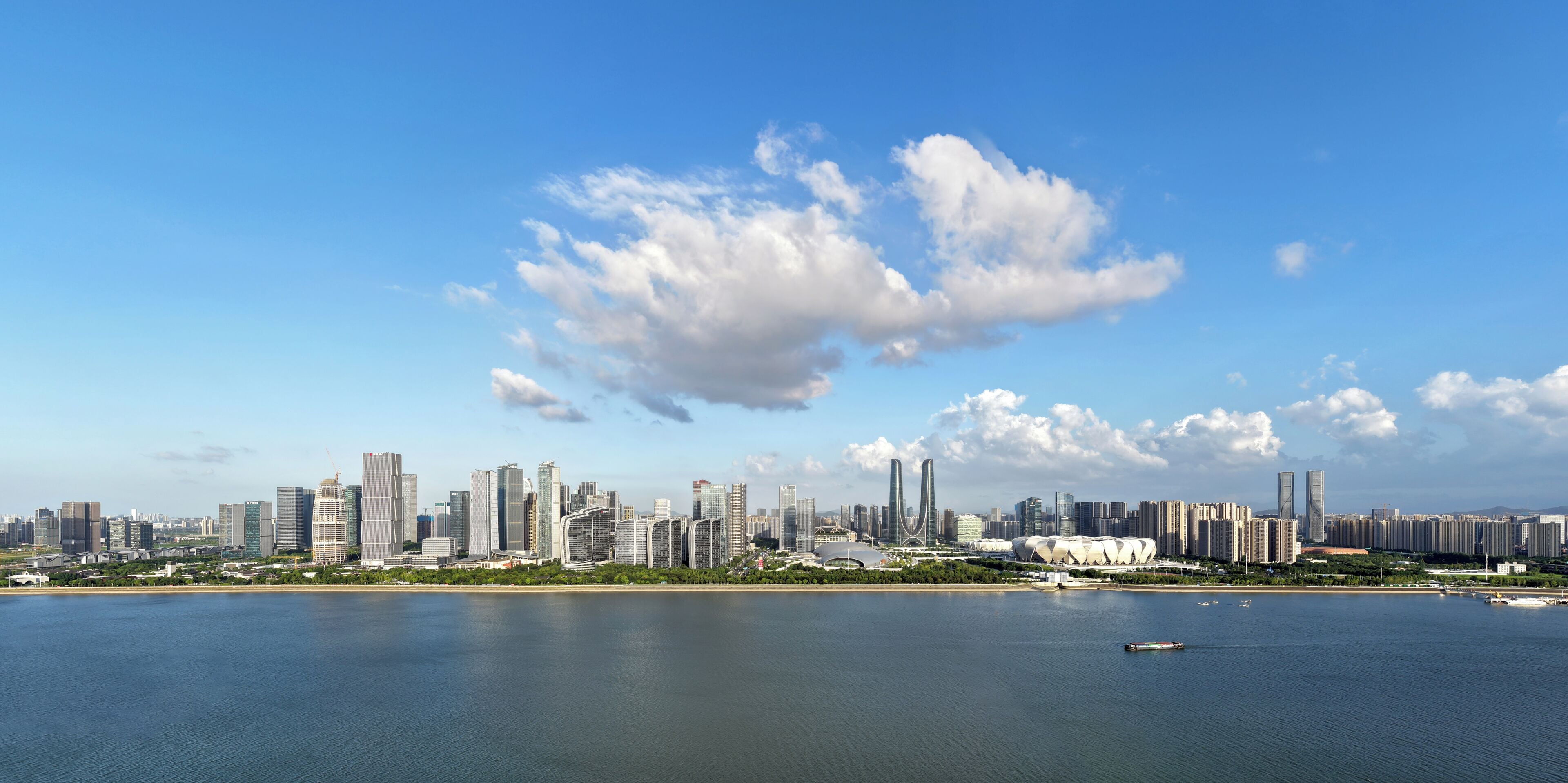 A city skyline with modern buildings, a waterfront, and a large stadium.