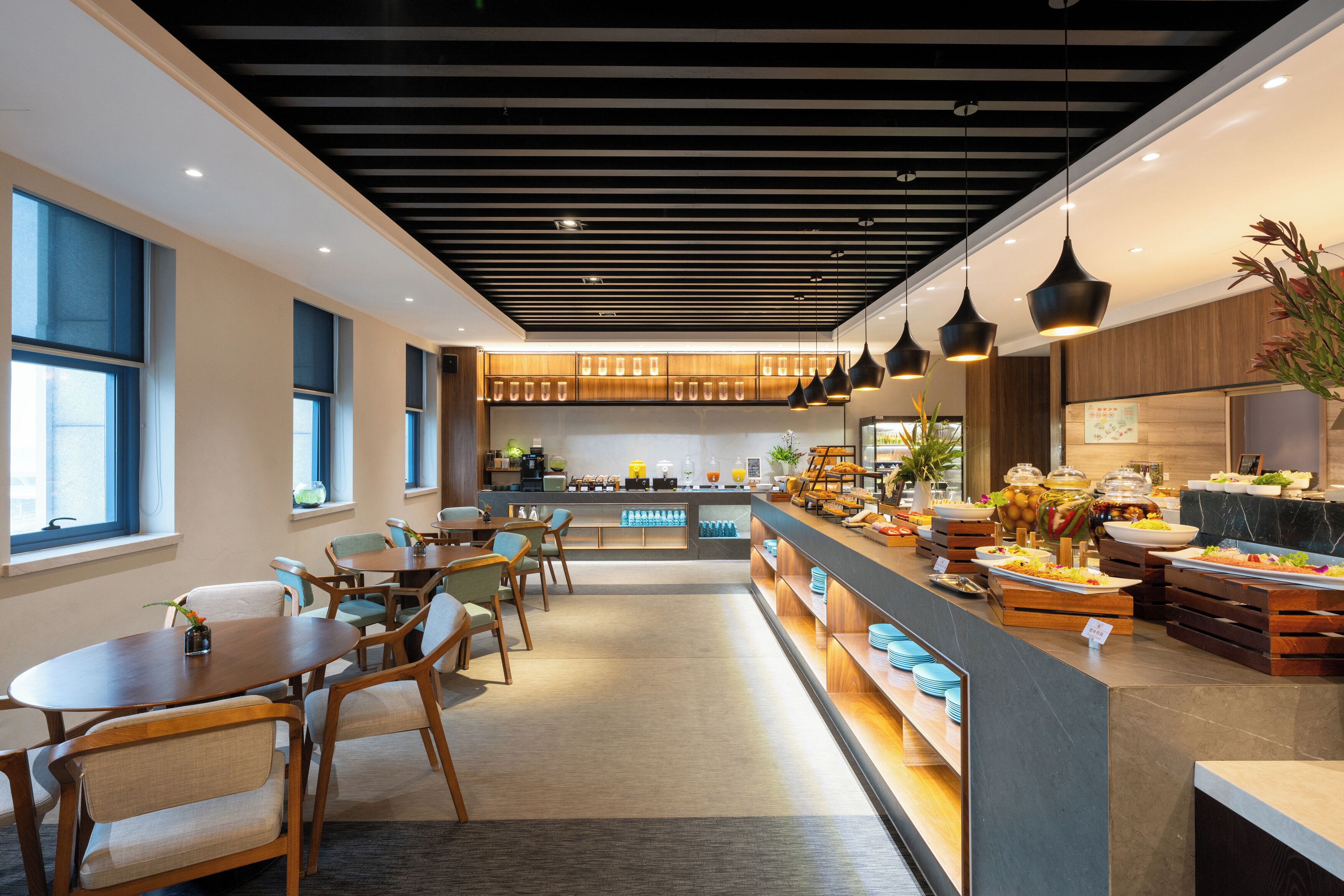A modern hotel lobby with a reception desk, seating area, and buffet.