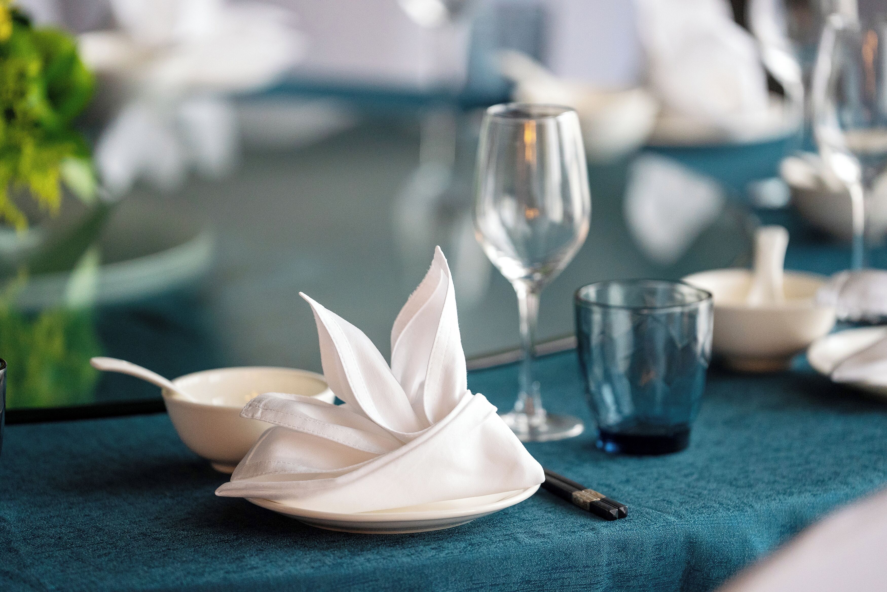 Une table dressée avec une serviette blanche, un verre et un bol.