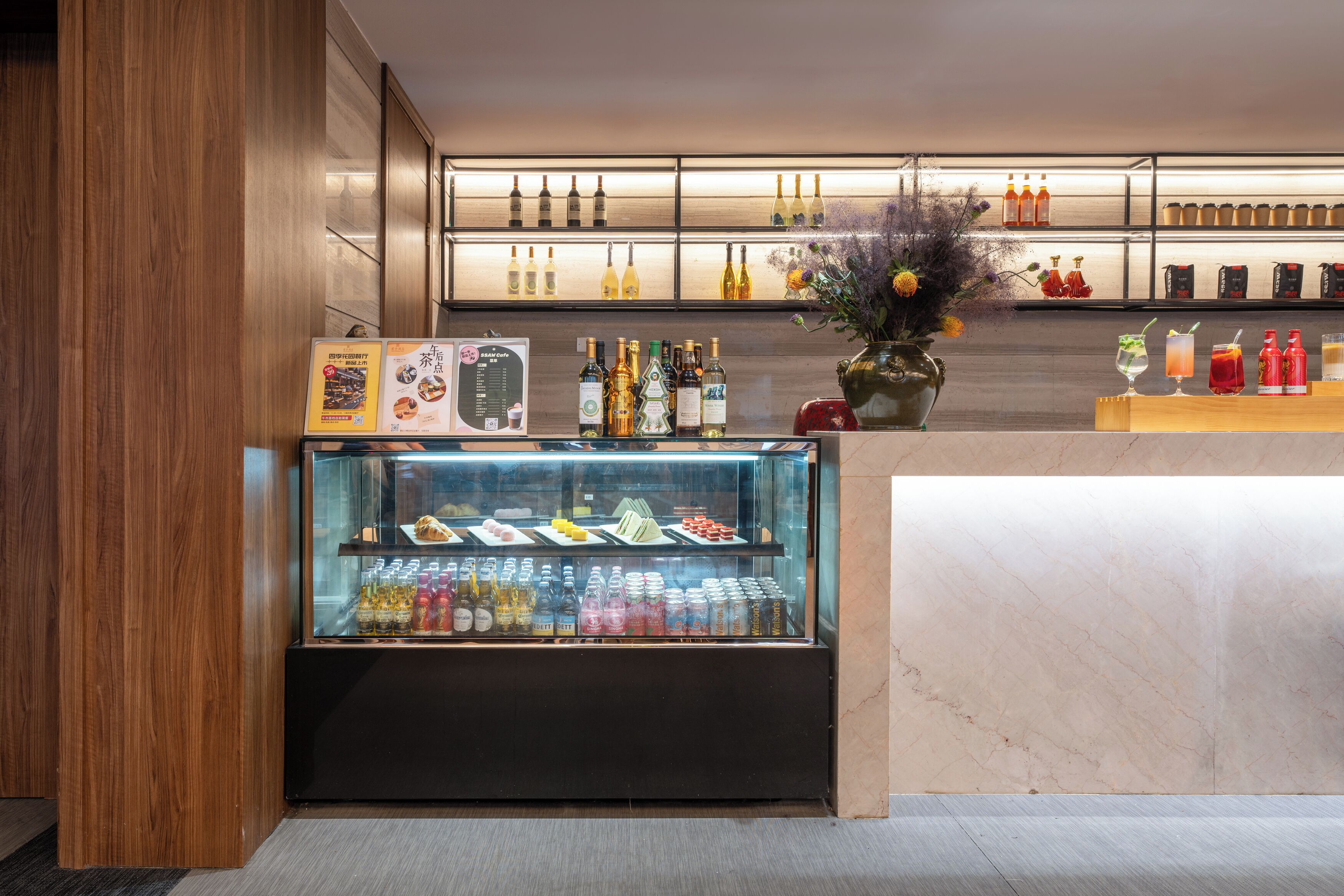 A bar area with a display case of beverages and a selection of bottles on shelves.