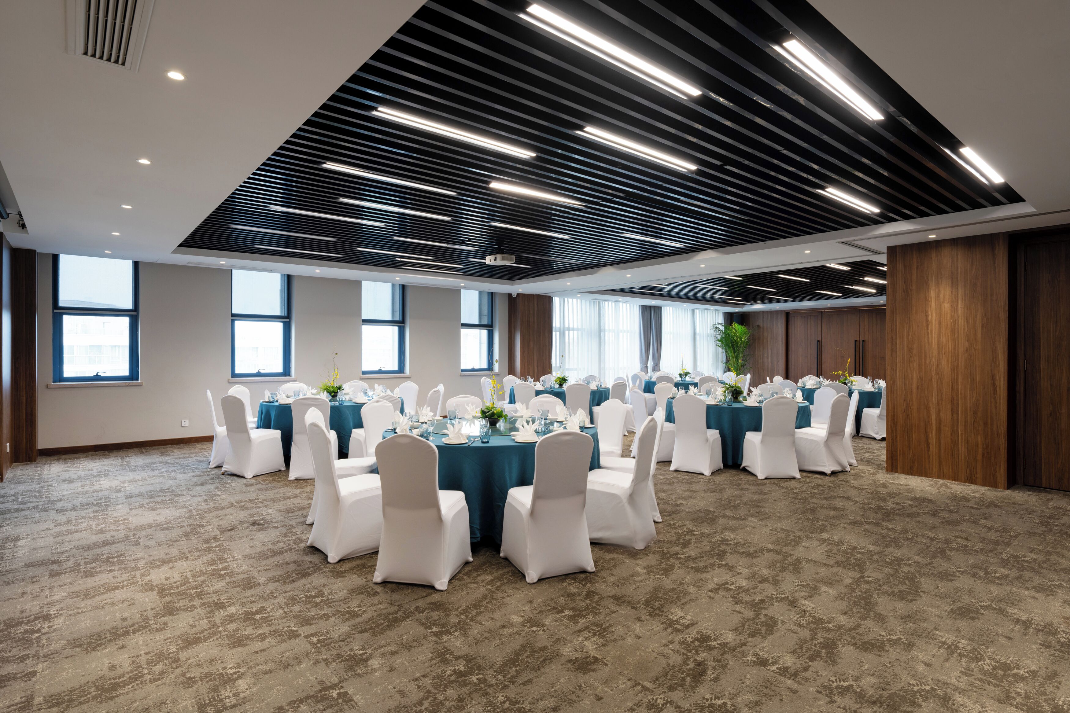 A conference room with round tables, white chairs, and a modern ceiling design.