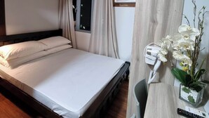 Una habitación de hotel con cama, escritorio con secador de pelo y ventana con cortinas.