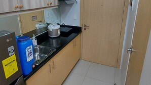 Una cocina compacta con refrigerador, lavamanos, estufa y gabinetes de madera.
